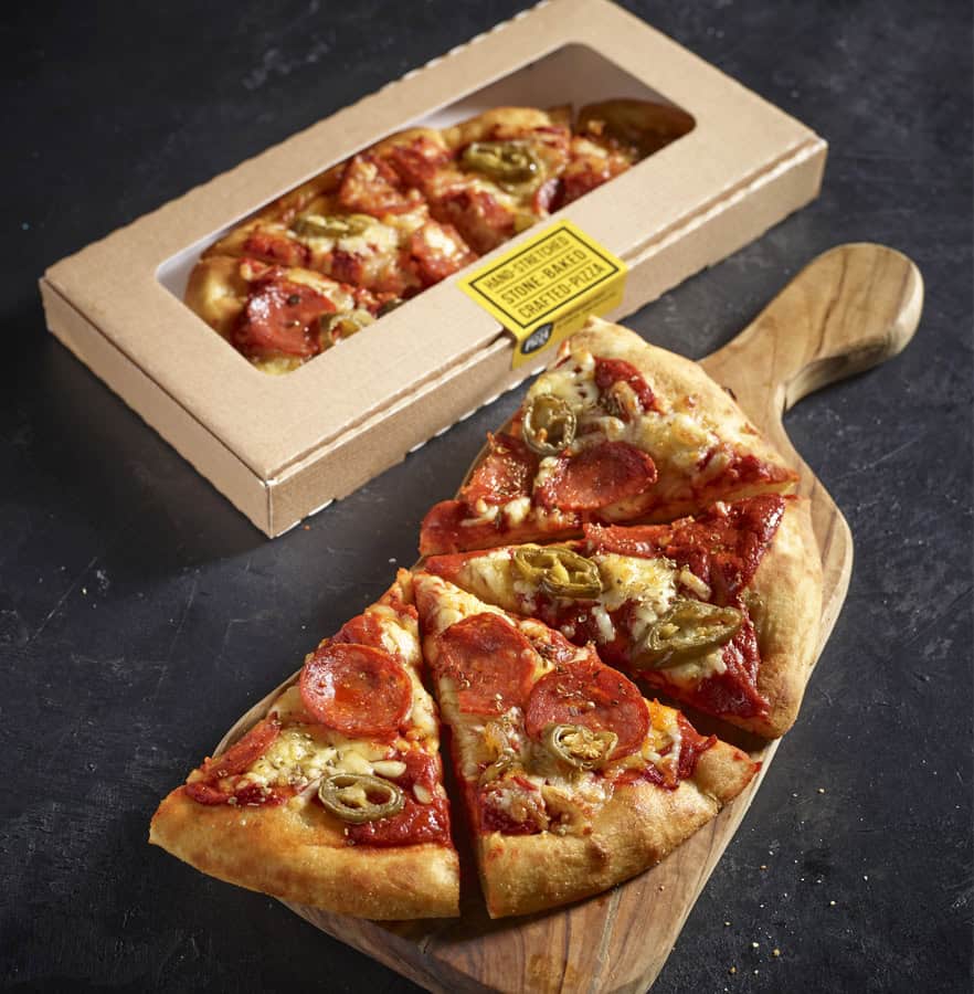Pepperoni and jalapeño pizza on wooden board