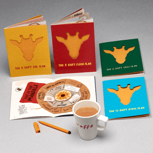 Colourful giraffe-themed notebooks beside a coffee mug
