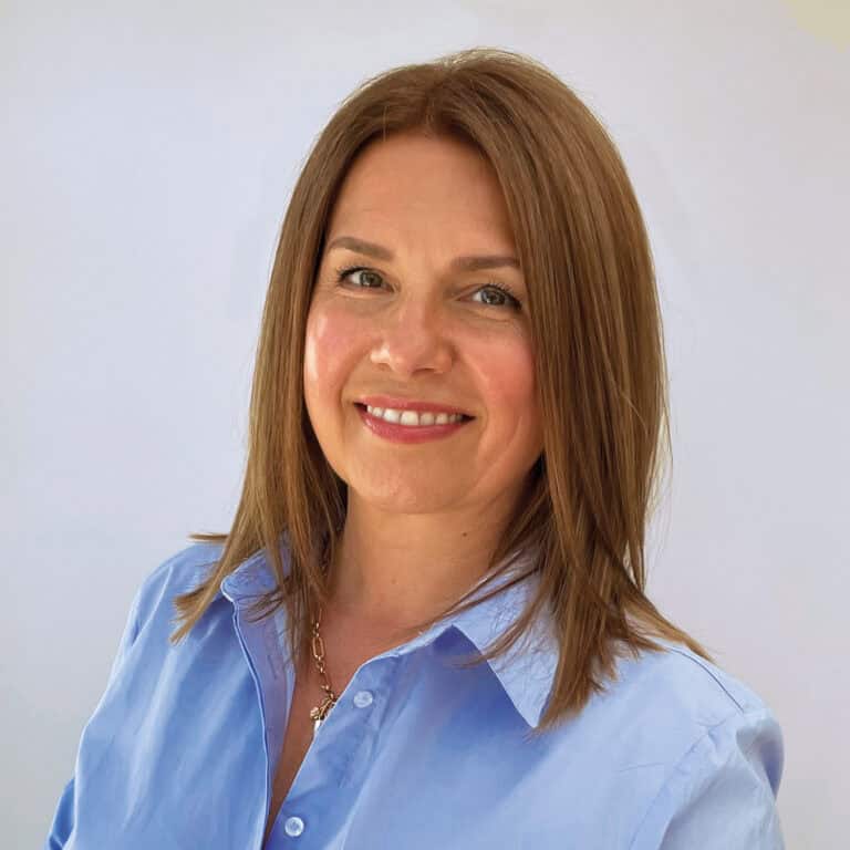 Smiling woman in blue blouse against plain background